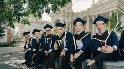 Un groupe de diplômés en toges et chapeaux célèbrent leur réussite en plein air.