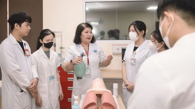 Groupe d'étudiants en médecine pratiquant des compétences avec un mannequin d'entraînement dans une salle de classe.