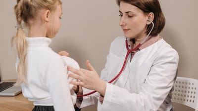 Médecin effectuant un examen de santé sur un enfant avec un stéthoscope dans un cadre clinique.