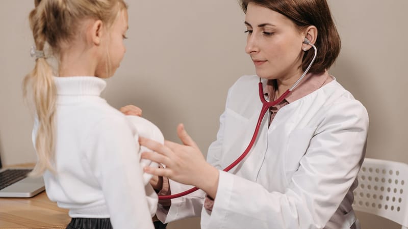 Médecin effectuant un examen de santé sur un enfant avec un stéthoscope dans un cadre clinique.