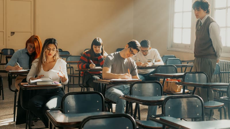 Des étudiants assistent à un cours dans une salle de classe d'une université de Buenos Aires, baignée de lumière naturelle.