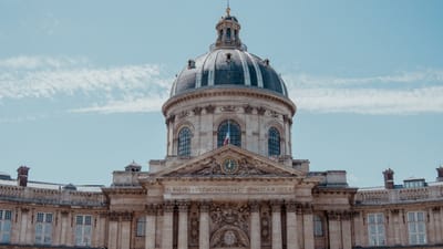 Vue de face du majestueux Institut de France à Paris avec un ciel bleu clair.