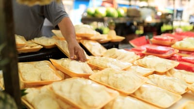 Une personne choisit des aliments frais emballés sur un marché en plein air.