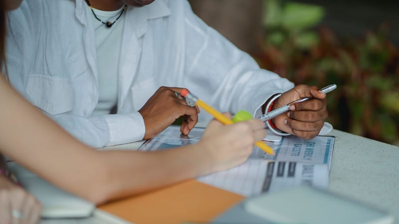 Un groupe diversifié d'étudiants collaborant en extérieur, prenant des notes et se préparant pour un projet.