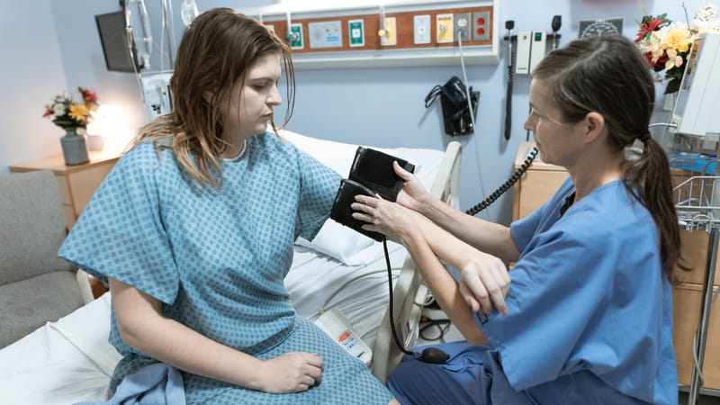 Une infirmière mesure la pression artérielle d'un patient dans une chambre d'hôpital, mettant l'accent sur les soins de santé et les soins médicaux.