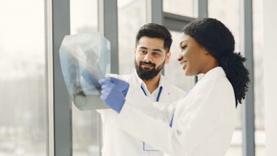 Deux médecins en blouses de laboratoire examinent une image radiographique dans un établissement médical lumineux.