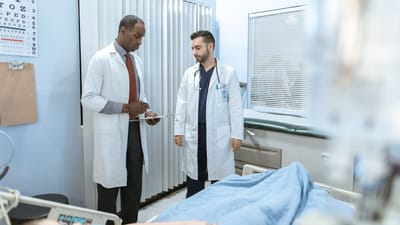 Deux médecins examinent le dossier d'un patient dans une chambre d'hôpital, mettant l'accent sur la coopération en matière de santé et les soins médicaux.
