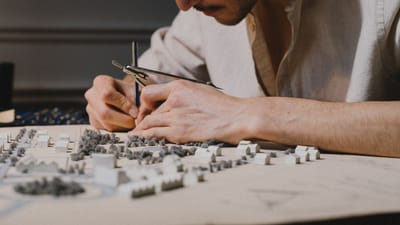 Architecte concentré sur la création d'un modèle détaillé à l'aide d'un compas à l'intérieur, mettant en avant la précision et la créativité.