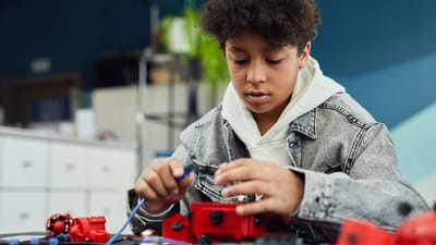 Garçon concentré travaillant sur un projet de robotique à l'intérieur, démontrant apprentissage et créativité.