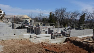 Chantier extérieur montrant des murs en blocs de béton et des échafaudages sous un ciel dégagé.