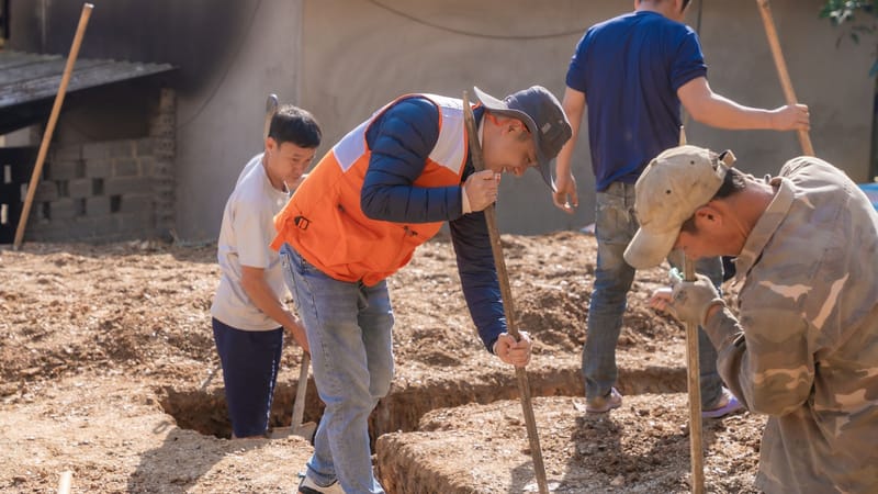 Groupe de travailleurs creusant des tranchées de fondation sur un chantier de construction en extérieur.