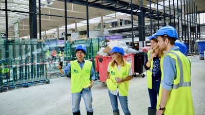 Groupe d'ingénieurs et d'architectes portant des équipements de sécurité sur un chantier, discutant des plans.