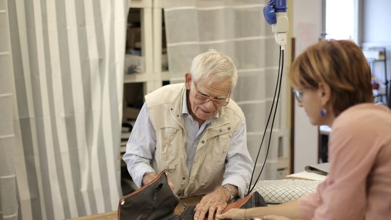 Artisan senior travaillant avec une assistante sur du tissu dans un cadre d'atelier.