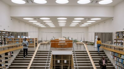 Intérieur spacieux de bibliothèque avec un design moderne, des étagères et des personnes dans les escaliers.