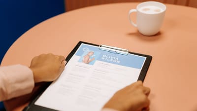 Gros plan sur des mains tenant un CV lors d'un entretien avec un café sur la table, mettant en avant le cadre professionnel.
