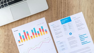Vue de dessus d'un ordinateur portable, de graphiques et d'un CV sur un bureau en bois, illustrant une analyse commerciale et une candidature.