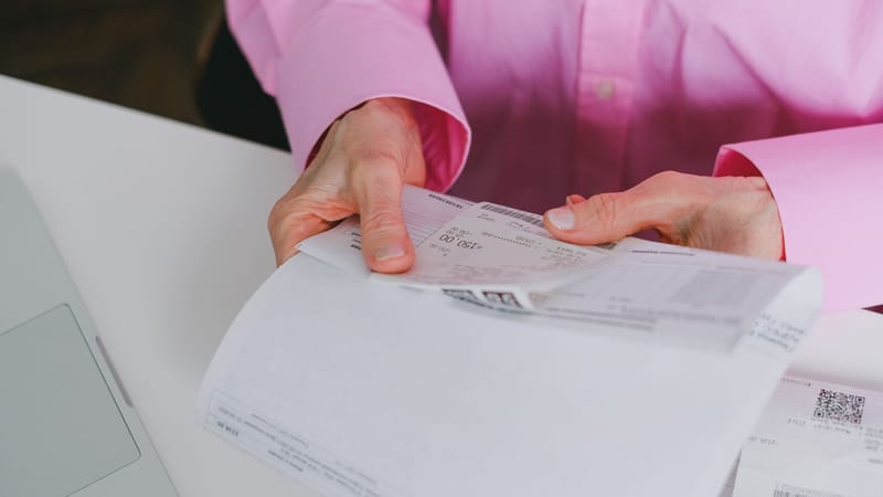 Personne d'affaires traitant des reçus en papier, méticuleusement organisés.