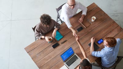 Vue en hauteur d'une réunion d'équipe collaborative dans un bureau avec des ordinateurs portables et du café.